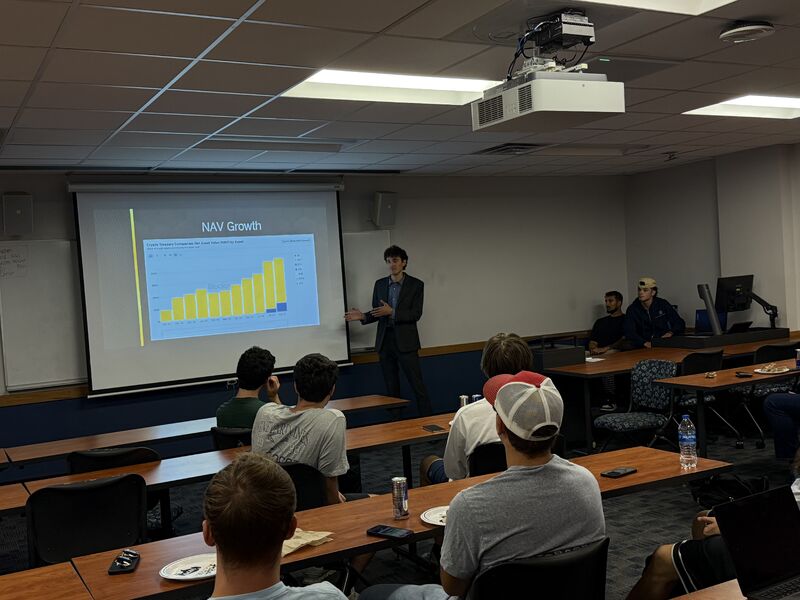 Zachary Epstein delivering a final presentation to a pro bono consulting client, with club members in the audience